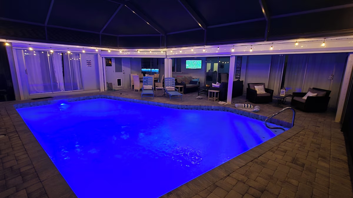 Aerial view of the home showing the screened pool, dock with seating area, and wide canal