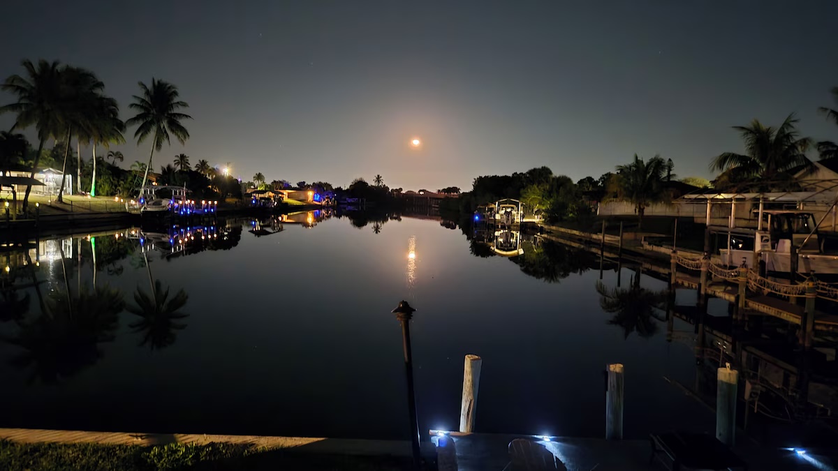 Rear view of the home showing the full screened-in pool enclosure with covered patio and colorful dining chairs