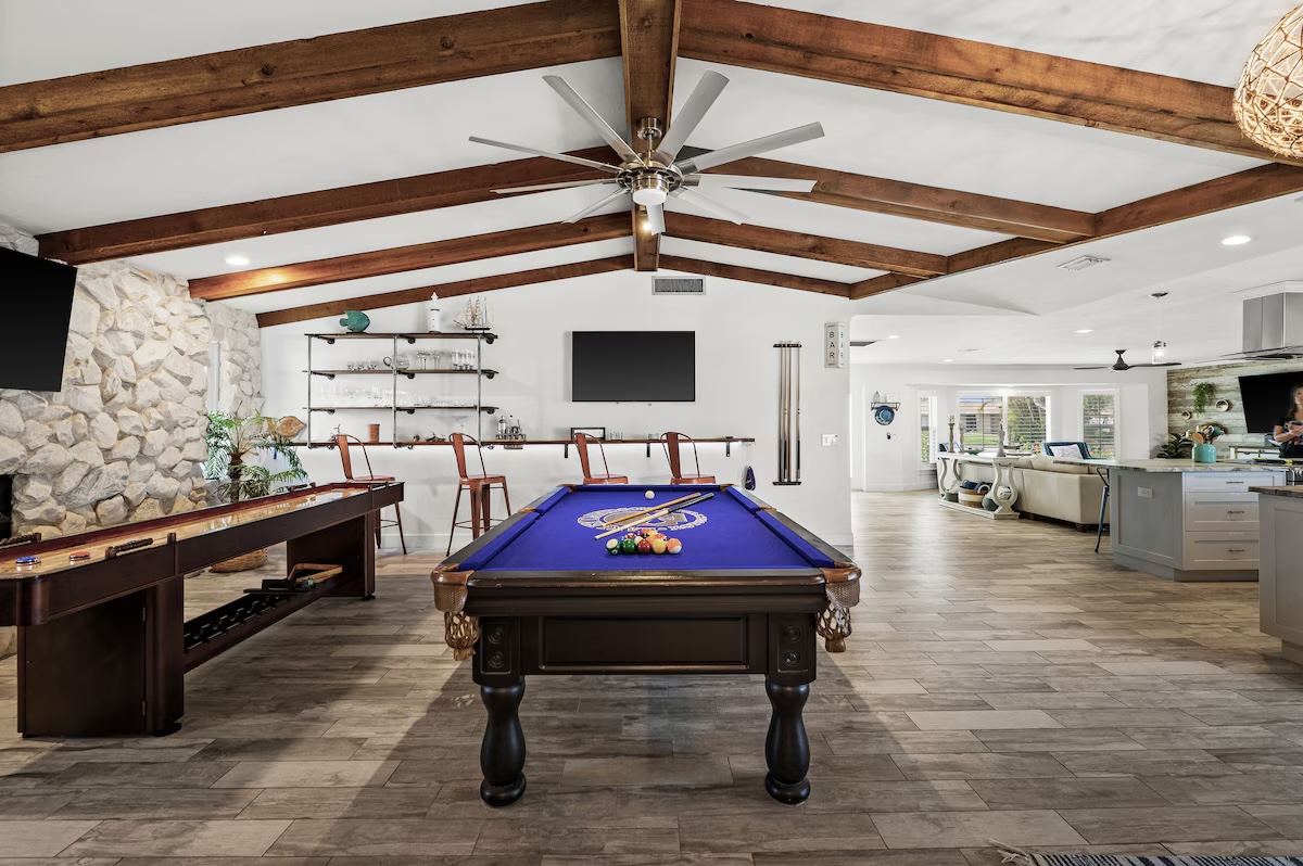 Game room with pool table and vaulted wood beam ceiling