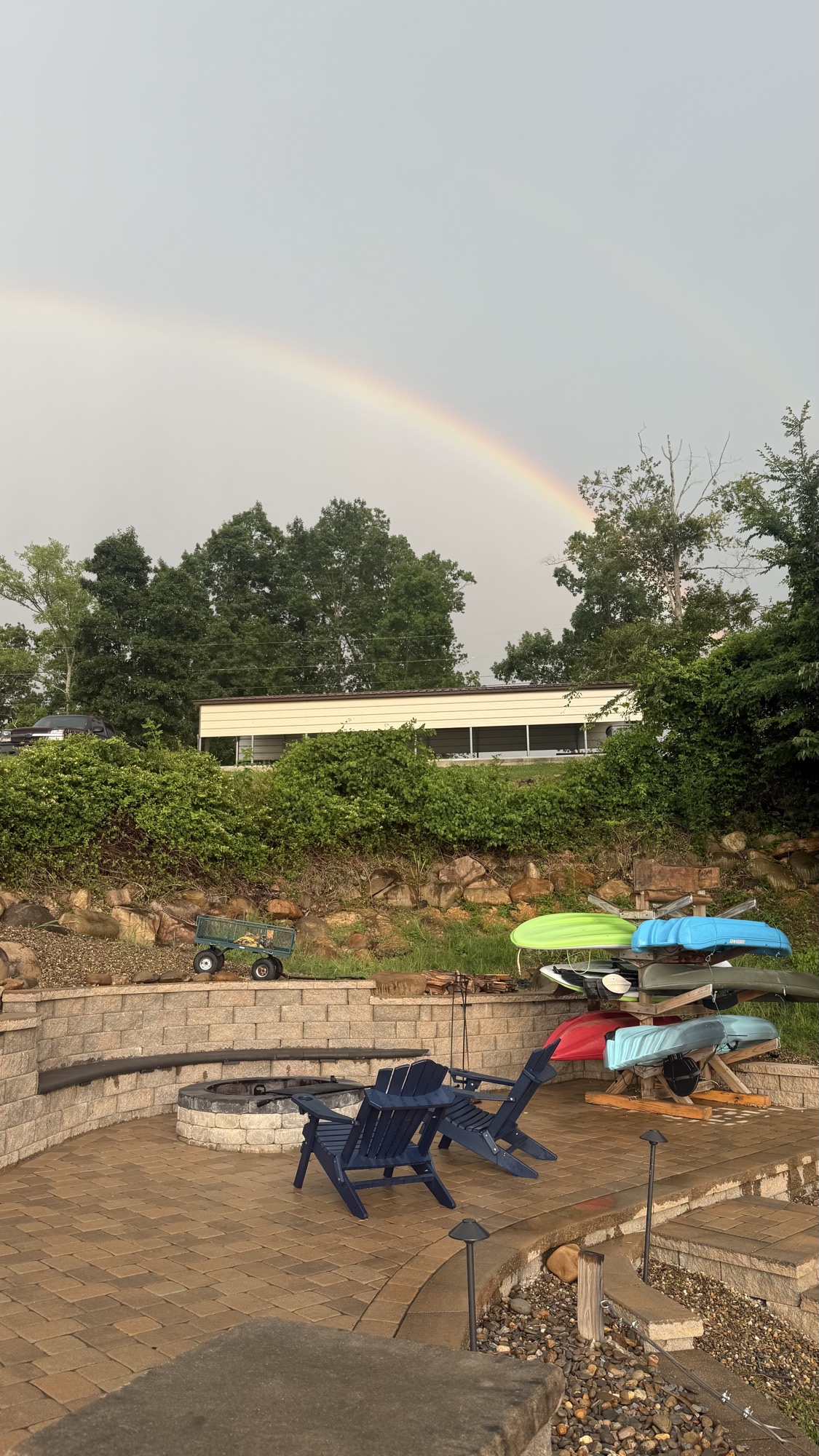 Full rainbow arcing over the firepit patio and kayak rack