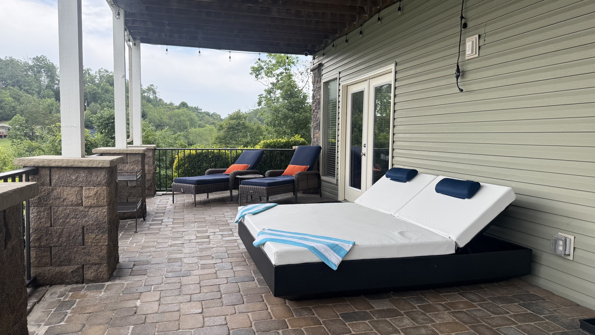 The downstairs porch lounge bed and chaises on the cobblestone patio