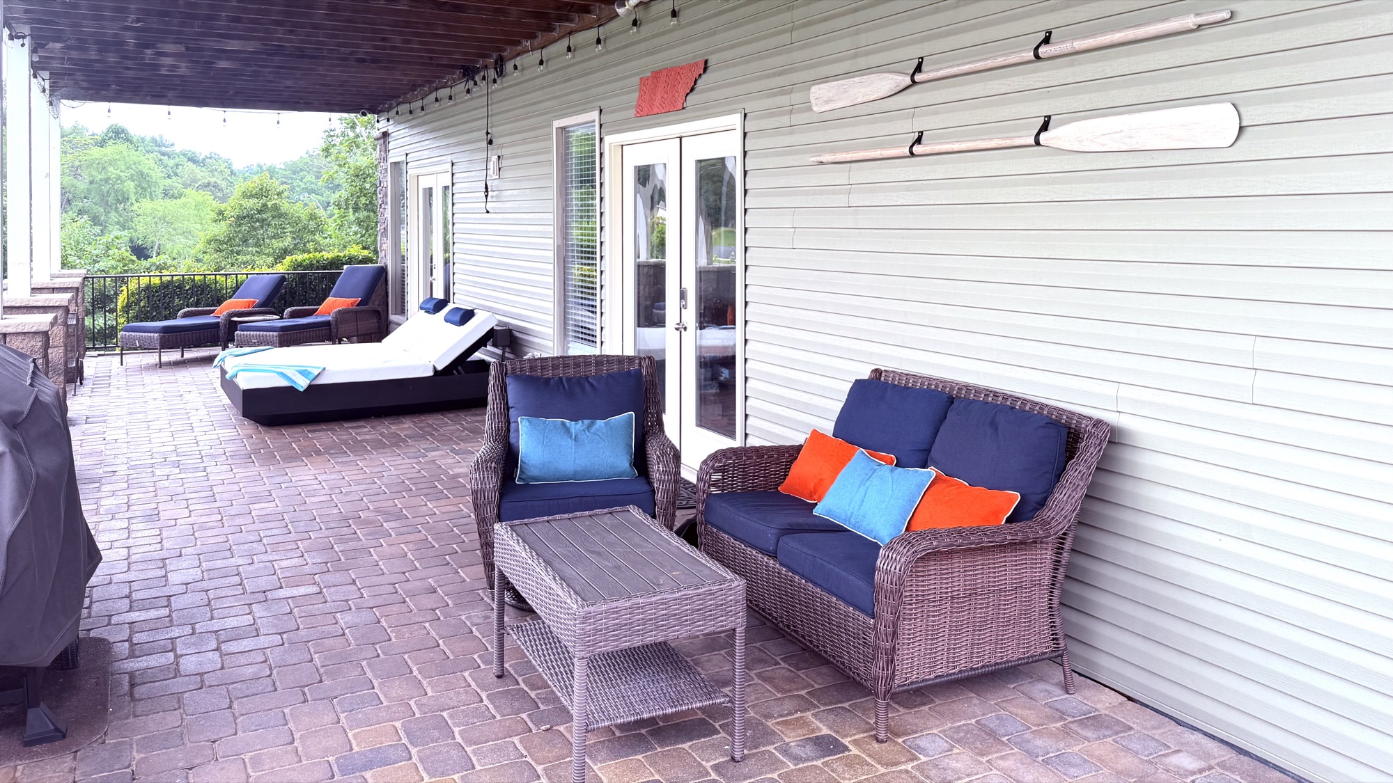 Wicker seating on the covered cobblestone patio with decorative oars on the wall