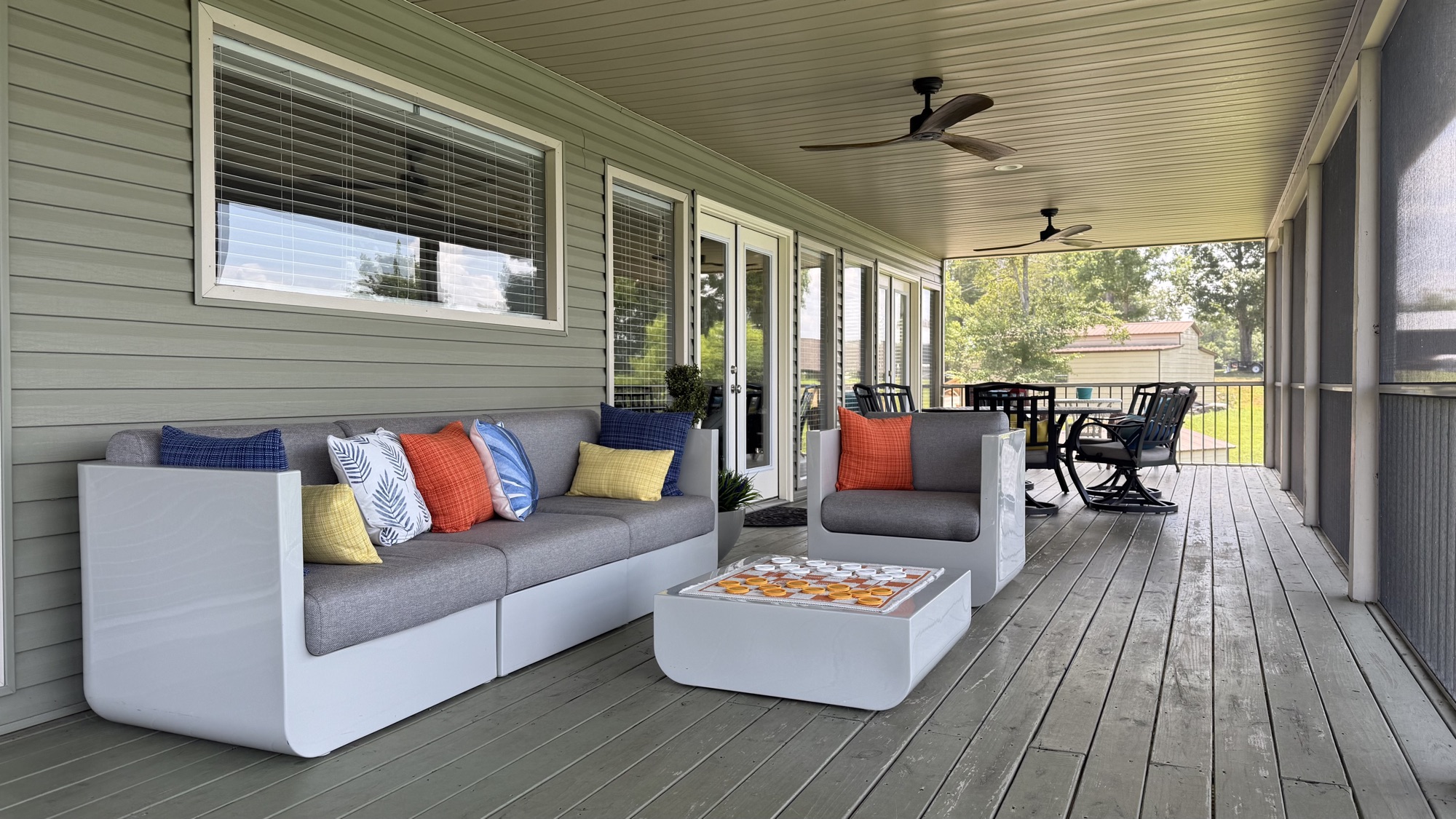 Screened porch lounge with modern white sectional and checkers table
