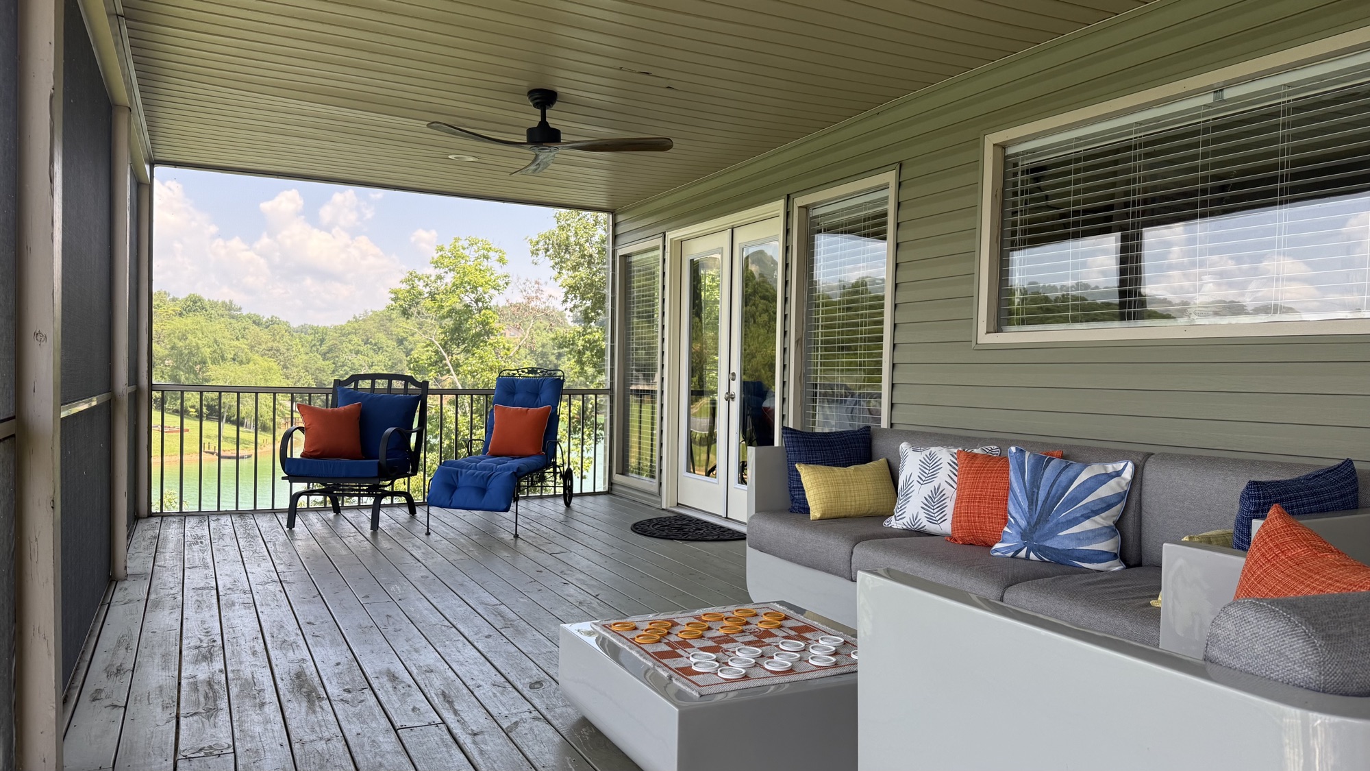 Screened upstairs porch with seating, ceiling fans, and Douglas Lake through the screens
