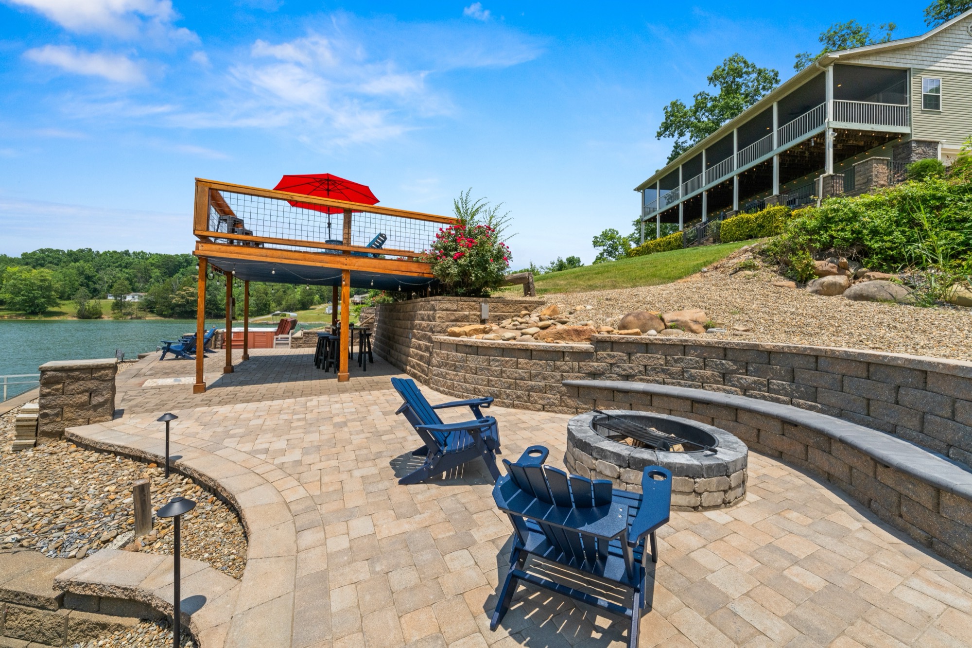 The fire pit on the paver patio with the pavilion, sundeck, and house on the hill behind