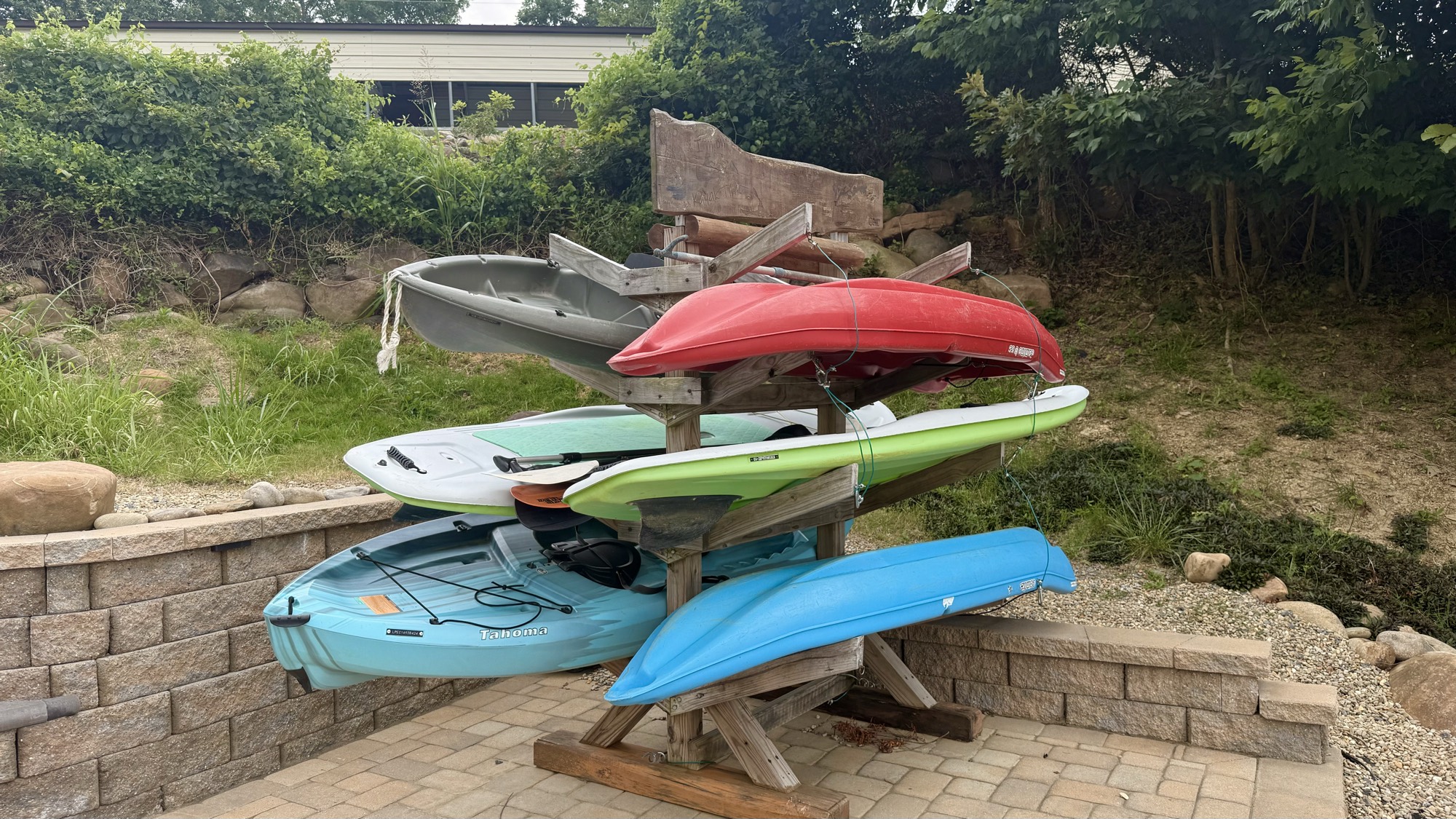 Close-up of the rack holding the full fleet — kayaks and stand up paddle boards ready to launch
